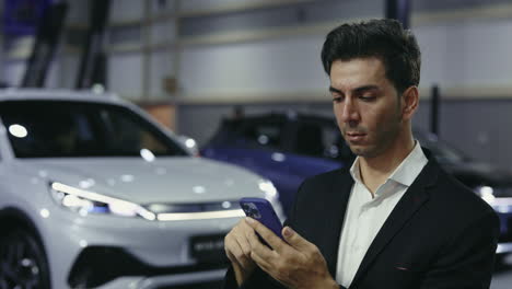 man looking at phone at a car show