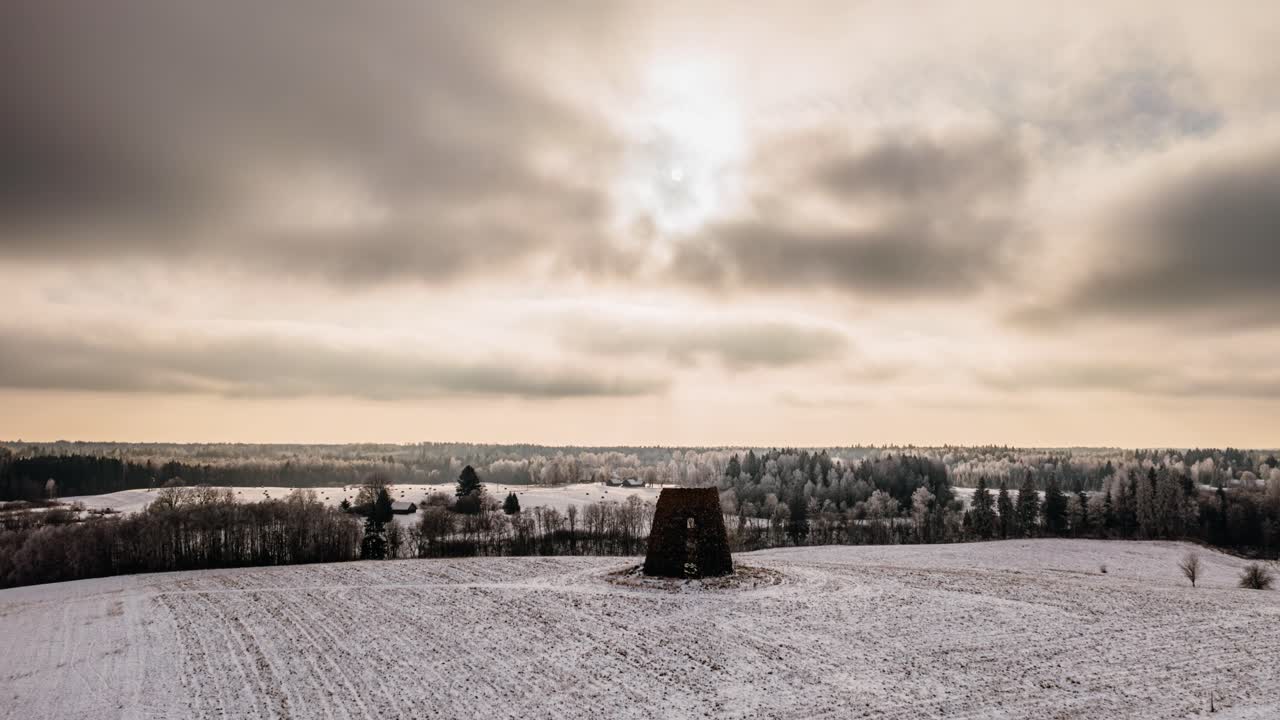 Drone hyperlapse of grey clouds in winter with snow covered countryside landscape.
