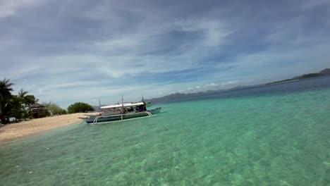 Fpv-drone-shot-along-turquoise-beach-shore-and-moored-boats,-Coron,-Palawan