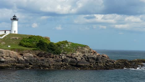 a panning view of cape neddick nubble lighthouse under a blue summer sky with puffy clouds