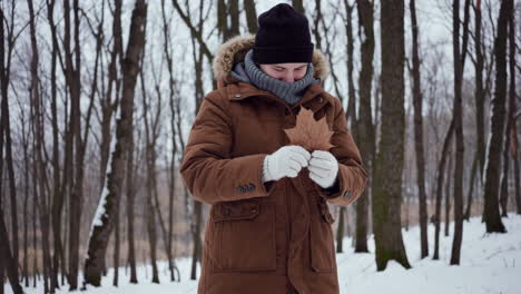 a person holding a leaf in a snowy winter forest