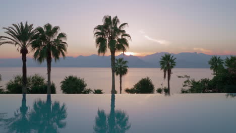 resort scene with swimming pool sea and mountains at sunset