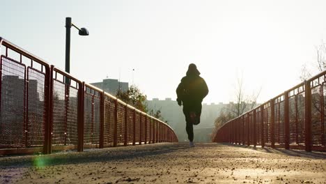 primer plano de un hombre que comienza su carrera en un puente - toma panorámica