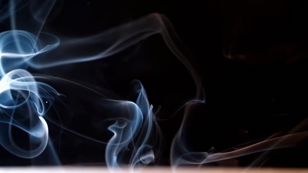 Video astratto di fumo vorticoso su uno sfondo scuro, ripreso da un'angolazione laterale.