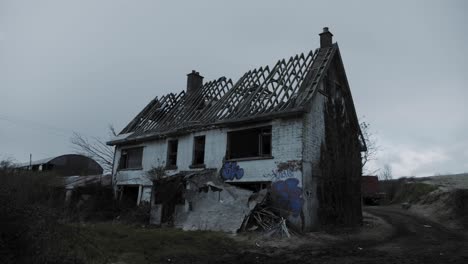 handheld approaching of the abandoned house with graffiti on a cloudy sky in northern ireland. -wide shot