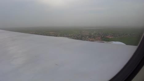 aircraft window view of airplane flying through beautiful clouds and landing on green landscape in dakar, senegal