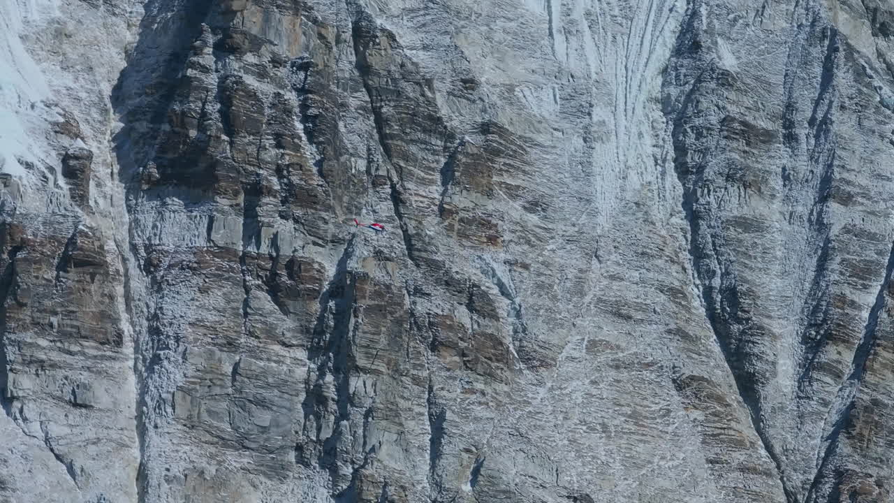 Drone footage of helicopter traveling Mount Everest region of Nepal, landscape snow-covered peaks, rugged rocky layers, Himalayan wilderness, vital rescue lifelines and exclusive travel experiences