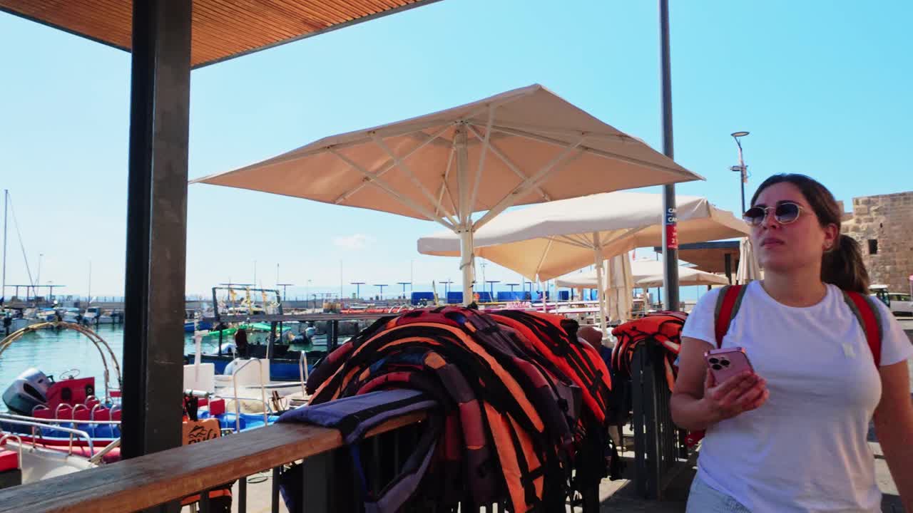 Vista posteriore di una turista che osserva le barche in una marina soleggiata.