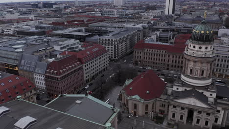 Forwards-fly-above-historic-buildings-in-city-centre.-Aerial-view-of-Konzerthaus-and-Franzosischer-Dom-on-Gendarmenmarkt.-Berlin,-Germany