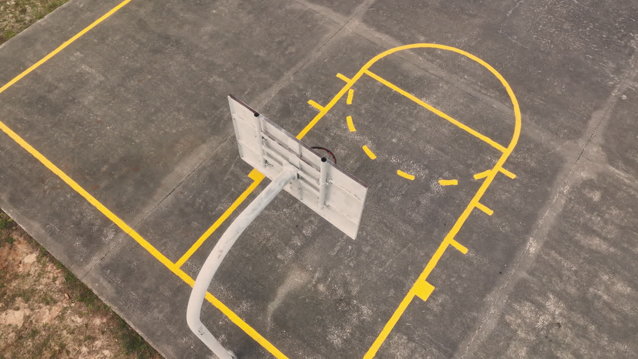 Aerial top down shot of empty basketball court with basketball hoop during sunny day
