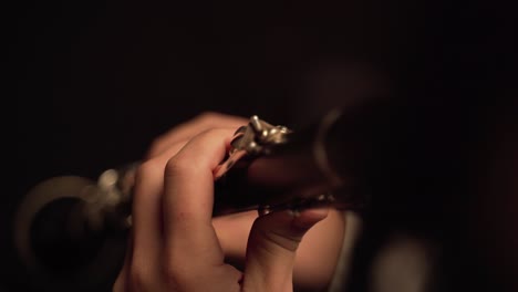 fingers player on clarinet, in a dark room