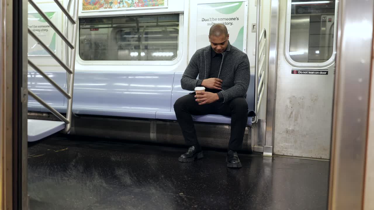 Uomo seduto in metropolitana con un caffè