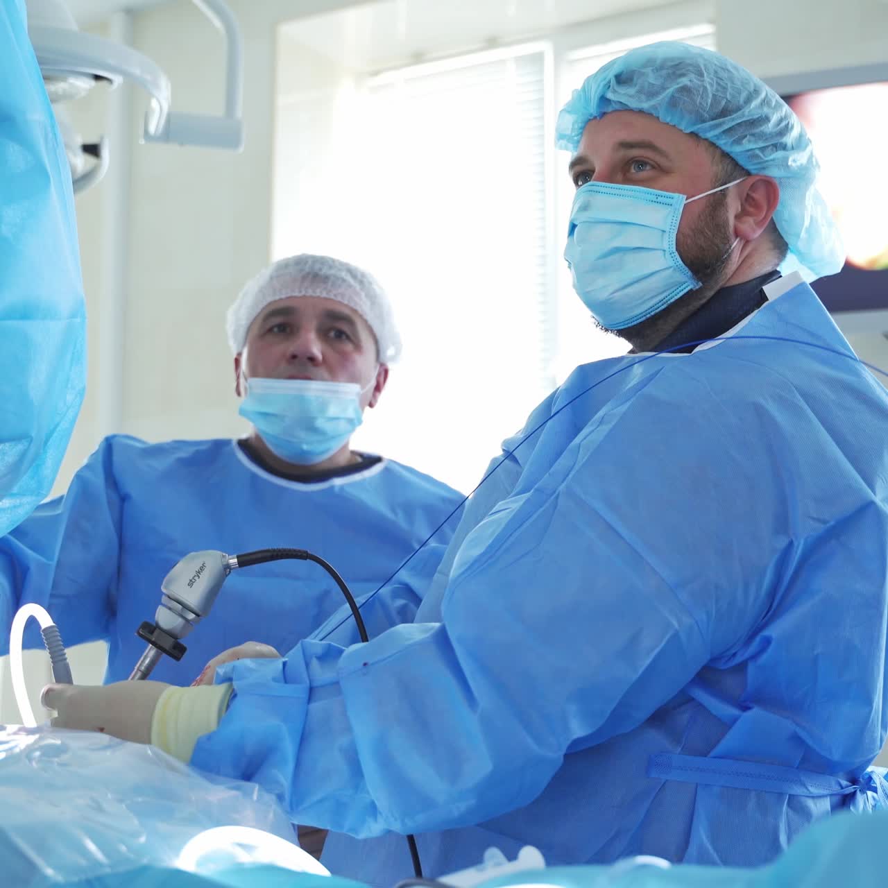 Surgeon during laparoscopy operation. Surgeons holding laparoscopic instrument while looking away with serious expression