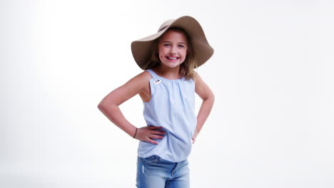 girl wearing hat poses against white studio background