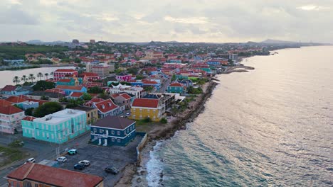 Punda-Pietermaai-Willemstad-Curacao-Bei-Sonnenaufgang-Mit-Sanftem-Licht-Und-Meereswellen-über-Farbenfrohen-Gebäuden