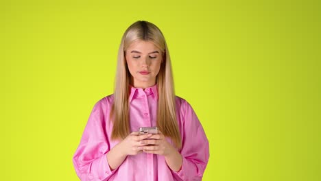 Blonde-Frau-Hält-Ein-Smartphone-SMS-Und-Lächelt,-Studioaufnahme