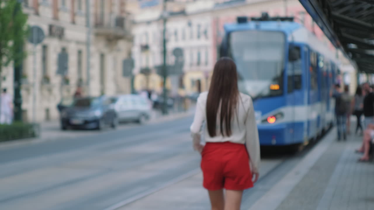 mujer esperando un tranvía en la ciudad