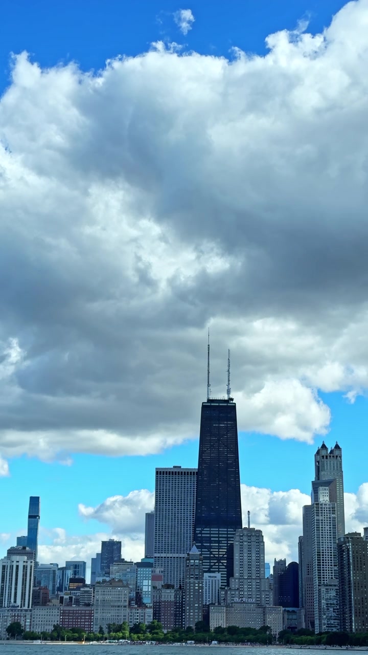 Vista do horizonte de Chicago com edifícios e nuvens durante o dia, com a luz do sol iluminando as estruturas e o céu.