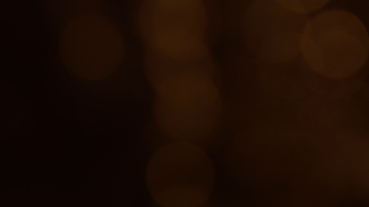 Cerchi di luce bokeh astratti e caldi in movimento su sfondo scuro
