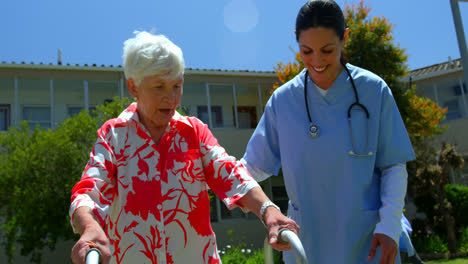 Vorderansicht-Einer-Kaukasischen-Ärztin,-Die-älteren-Patienten-Hilft,-Mit-Einem-Rollator-Im-Garten-Von-Nu-Zu-Gehen