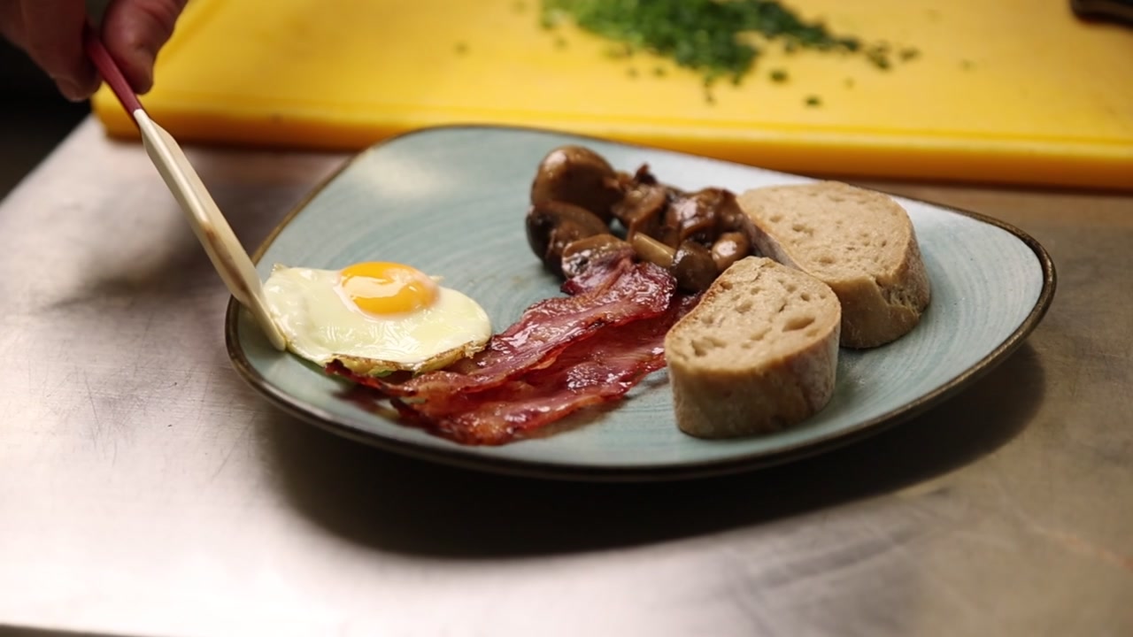 Servire uovo fritto, pancetta, funghi e pane per colazione