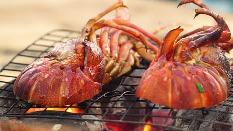 lobster halves on grate are grilled on open fire small charcoal stove, close up