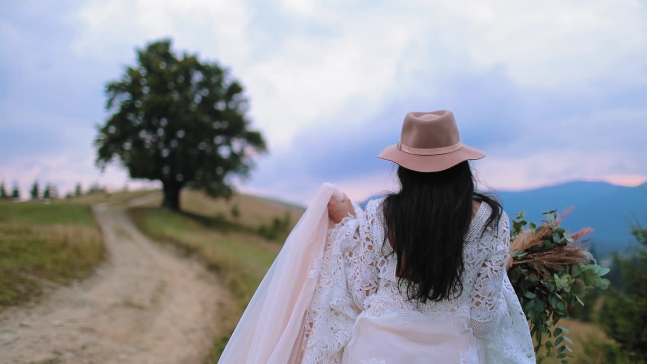 Bride posing in wedding dress. Young bride looks happy posing on the mountain