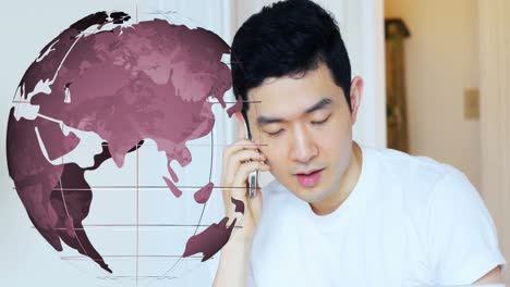 Animation-of-spinning-globe-over-asian-man-talking-on-smartphone-at-home