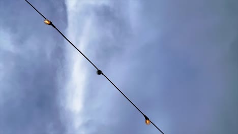 bombillas en una cuerda de luz con un lapso de tiempo cloudscape en el fondo - mirando hacia arriba