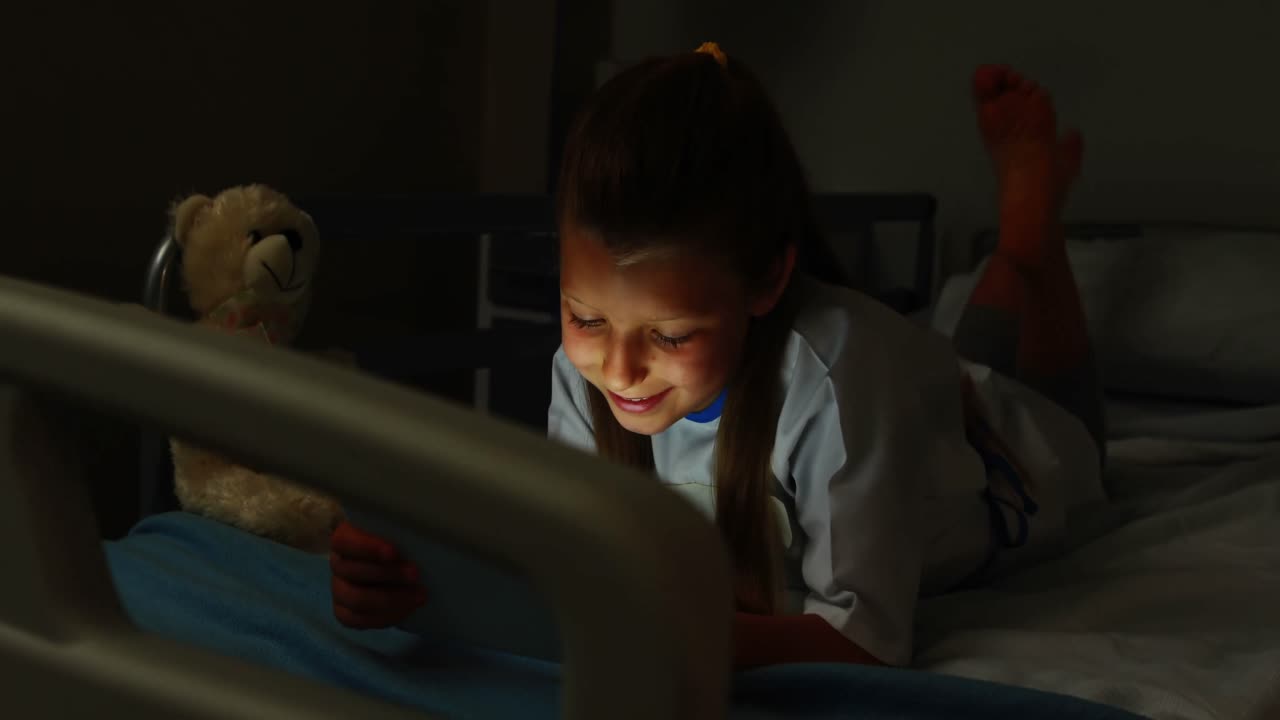 침대에 디지털 태블릿을 사용하는 아픈 소녀