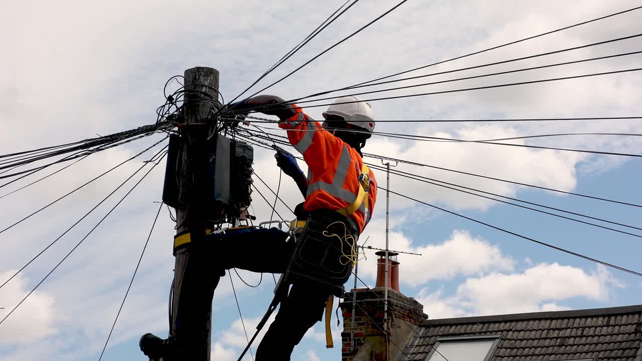 ingeniero de telecomunicaciones realizando tareas de mantenimiento en la parte superior de un poste telefónico