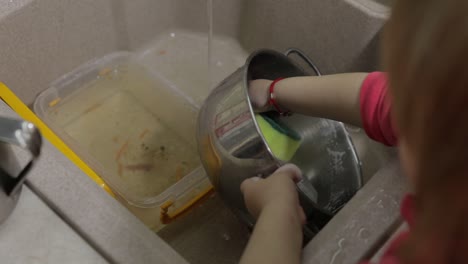 child washing dishes in the kitchen. close up of girls hands