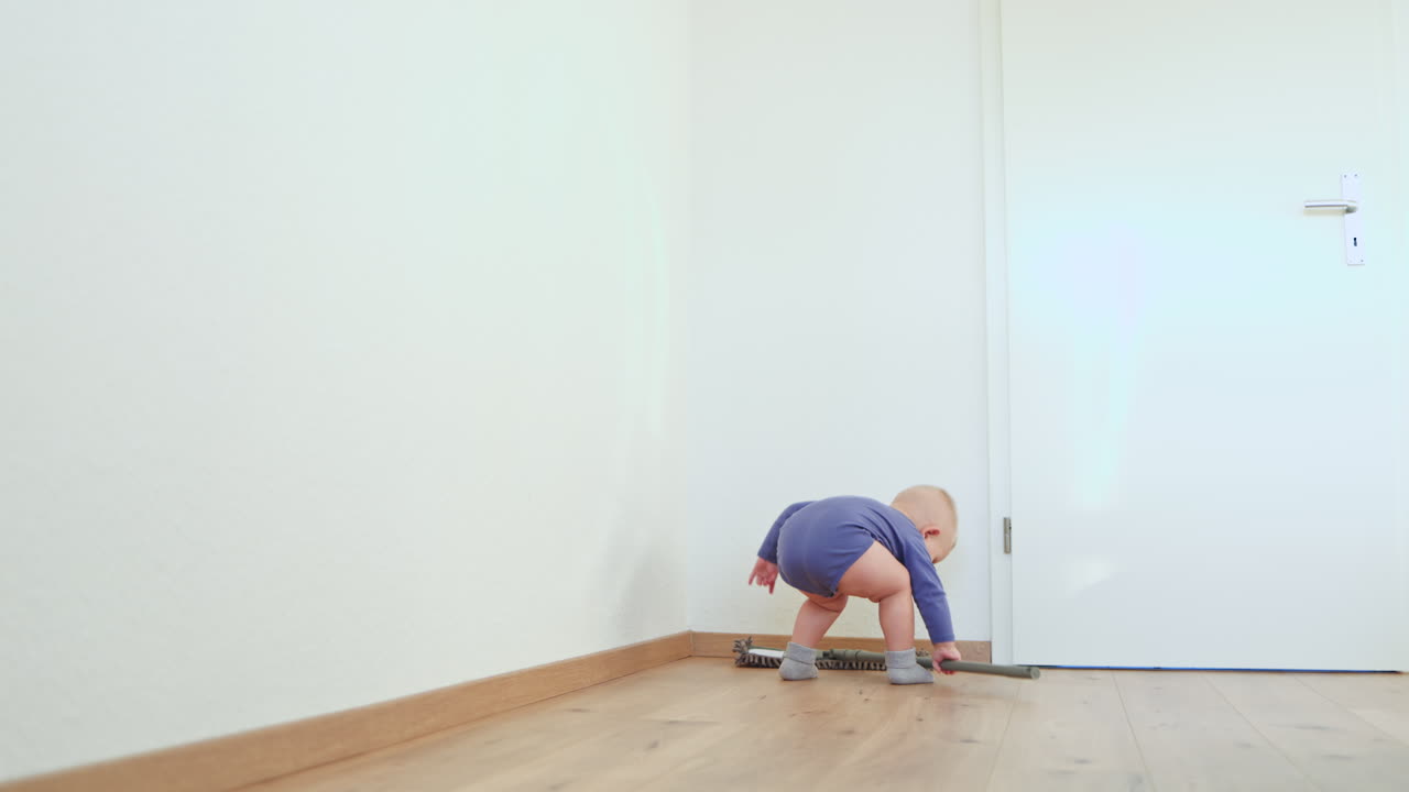 Un bambino piccolo lava il pavimento con un mop. Il bambino aiuta a pulire il pavimento. Un bambino in un body di cotone