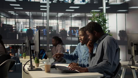 two people working together on computers in an office