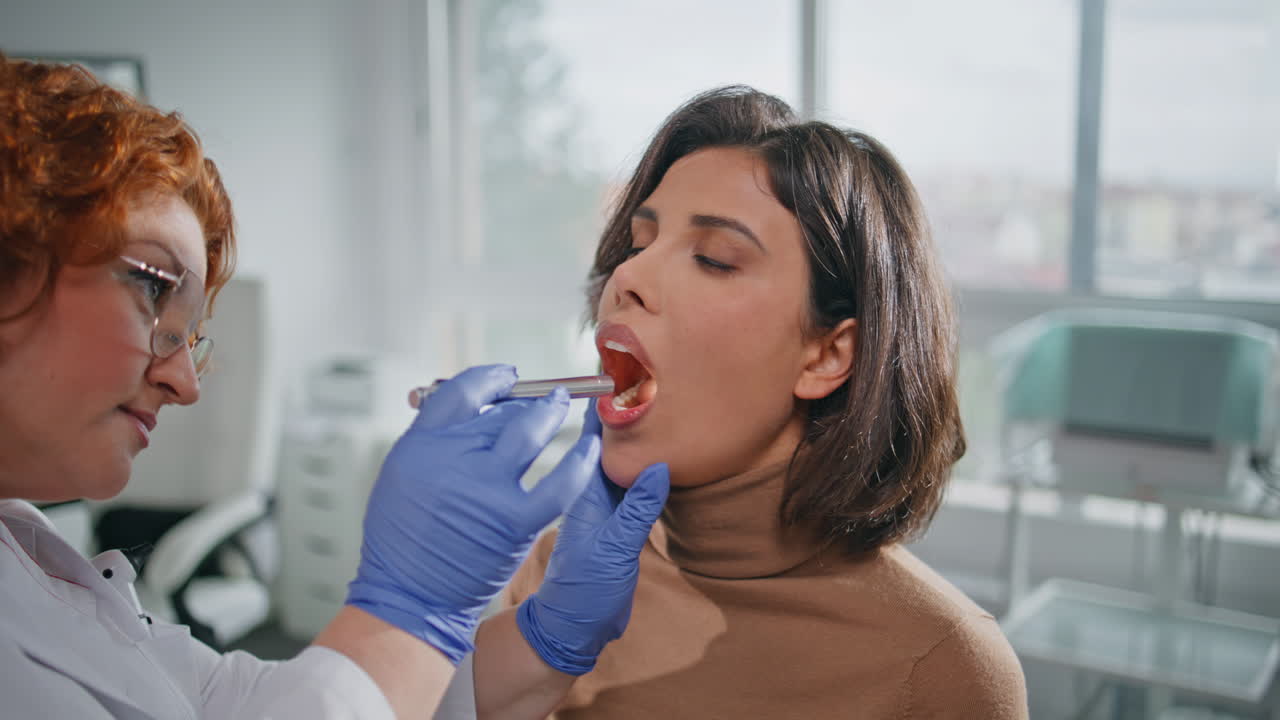 Clinic patient open mouth at health checkup closeup. Practitioner oral exam