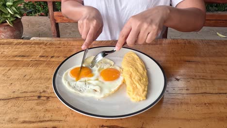 person cutting and eating eggs and omelette