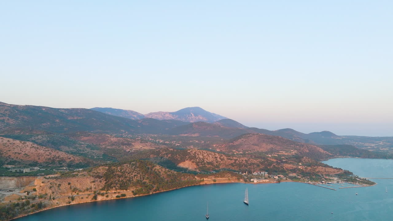 Aerial View of a Coastal Bay with Mountains and a Sailing Boat