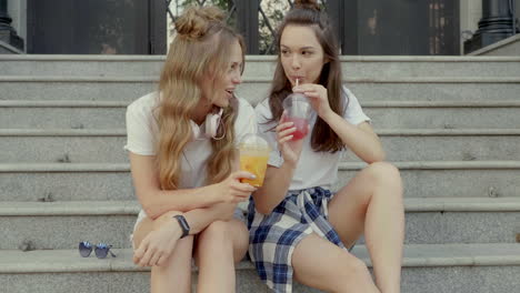 two friends enjoying drinks on the stairs