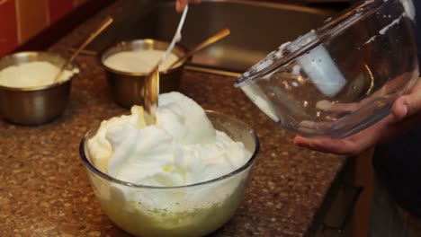 Close-up-of-hands-carefully-mixing-soft-peaked-white-eggs-to-yolk,-static