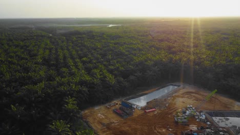 Cinematic-4K-Drone-Footage-of-Onshore-Drilling-Rig-equipment-structure-for-oil-exploration-and-exploitation-in-the-middle-of-jungle-surrounded-by-palm-oil-trees-during-sunset-and-high-oil-price