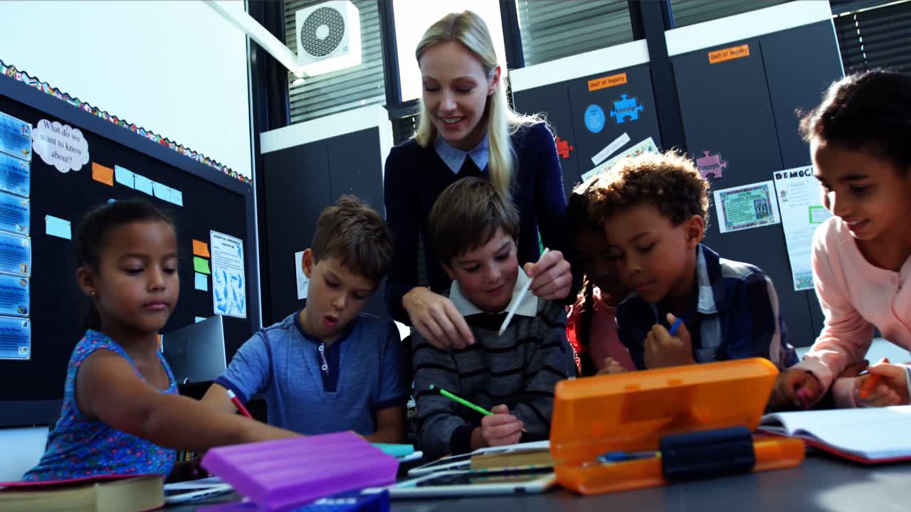 Teacher helping schoolkids with their homework in classroom