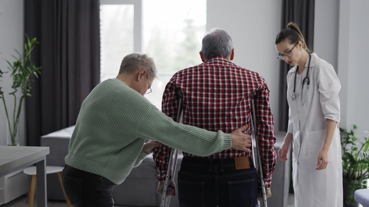 anciano dando sus primeros pasos con muletas en la clínica