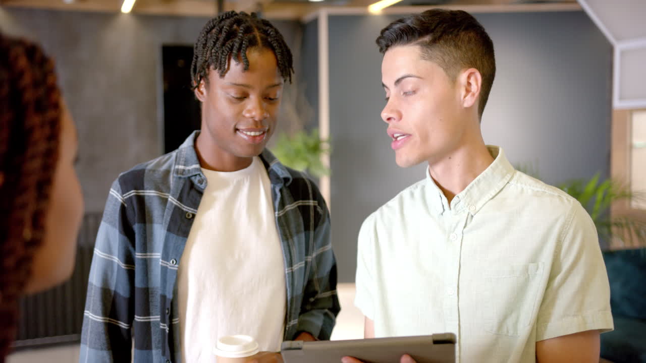 Discussing project, two colleagues looking at tablet in modern office setting