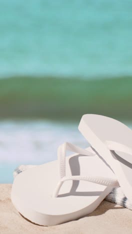 video vacaciones de verano verticales concepto de chanclas toalla de playa en la arena contra el fondo del mar