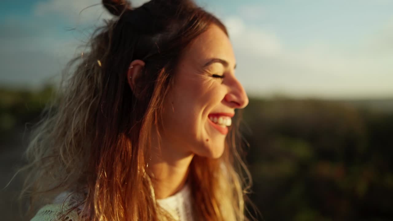 Portrait of a cheerful young Spanish woman laughing and smiling to camera at sunset