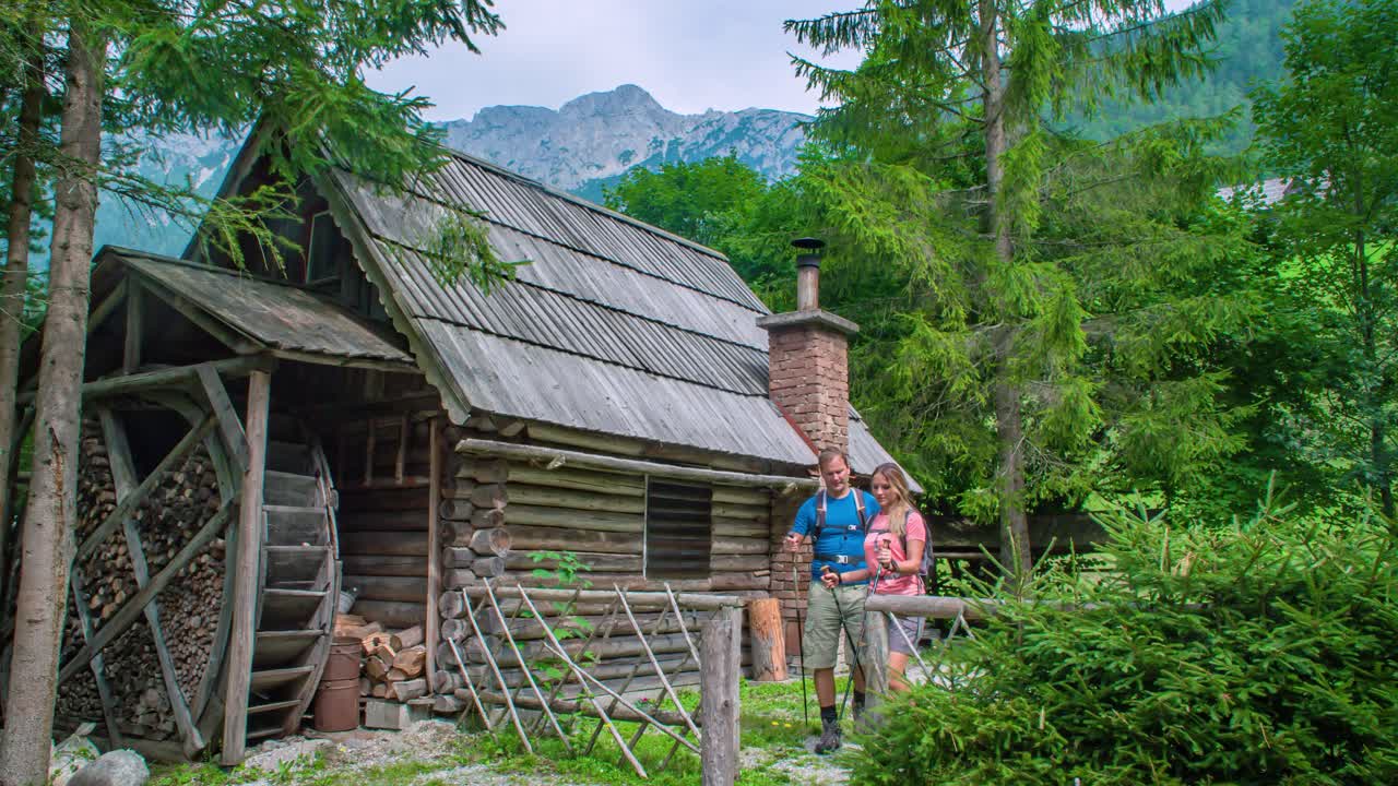Walking by a wooden mountain cabin with old water mill. Slowmotion hiking adventure. Topla Valley, Slovenia