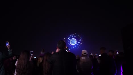 Spektakel-Am-Himmel:-Fesselnde-Nächtliche-Drohnenshow-Lockt-Menschen-Zum-Beobachten-Von-Menschen-Und-Zum-Filmen-Mit-Dem-Smartphone-An