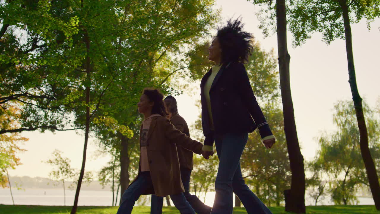 Child Walking Holding Parents Hands In Green Park. Happy Family Time ...