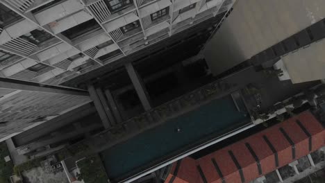 Top-down-view-of-swimming-pool-with-woman-swimming-in-Kuala-lumpur,-aerial