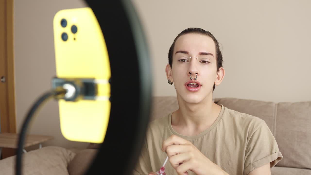 Young adult beauty vlogger applying makeup in front of ring light